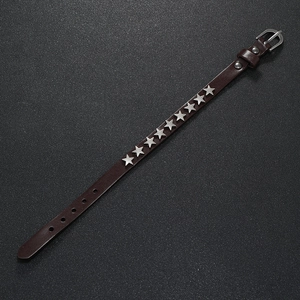 Detail of punk leather bracelet featuring silver star studs and adjustable pin buckle strap