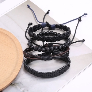 Détail d'un lot de quatre bracelets vintage en cuir tressé sur marbre et bois clair