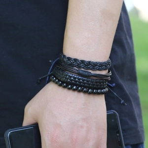 Gros plan de bracelets multicouches en cuir noir avec cordes tressées et perles pour hommes