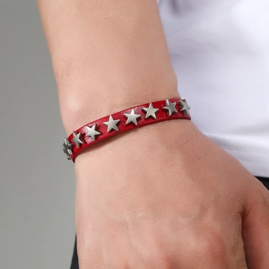 Close-up of red leather punk bracelet featuring silver star studs worn on a wrist