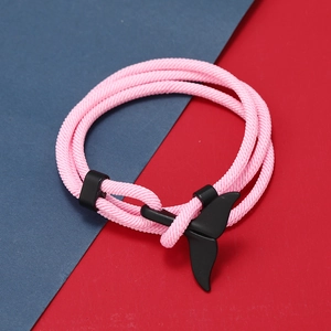 Dettaglio del bracciale a corda intrecciata rosa con ciondolo a coda di balena nero opaco su sfondo colorato