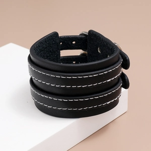 Détail d'un bracelet en cuir PU noir avec surpiqûres blanches et boucles en métal argenté