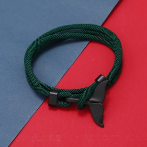 Dettaglio macro del braccialetto intrecciato verde scuro con chiusura a coda di balena