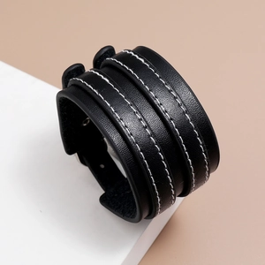 Détail du bracelet en cuir PU noir avec coutures contrastées blanches et œillets en métal