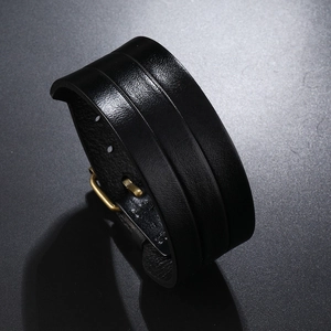 Détail d'un bracelet en cuir noir vintage avec boucle en métal bronze et trous de réglage