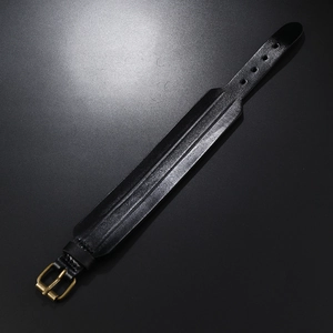 Détail d'un bracelet en cuir noir vintage avec surface texturée et boucle en bronze