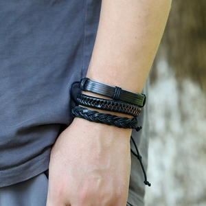 Close-up of three-piece black woven leather bracelet set with adjustable cords on wrist
