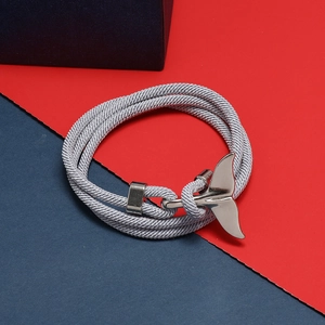 Dettaglio macro di un bracciale intrecciato grigio con ciondolo a coda di balena