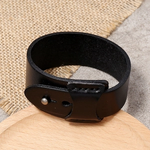 Gros plan d'un large bracelet manchette en cuir noir avec texture lisse et fermoir réglable