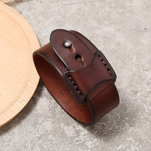 Vue détaillée du bracelet de force en cuir marron avec rivets métalliques et coutures