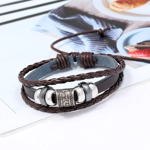 Macro detail of multi-layer leather braided bracelet with polished metal beads and vintage charms
