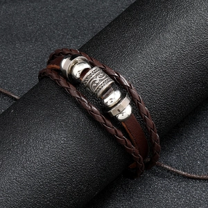 Close-up of vintage brown leather braided bracelet with tribal engraved metal charms