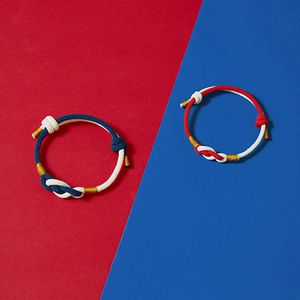 Handmade woven couple bracelets with red, blue and yellow cords in a modern knot design