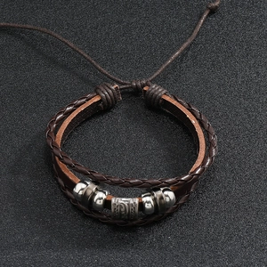 Detail of vintage braided brown leather bracelet with silver metal beads and ethnic tube