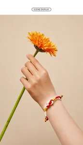 Handwoven red and white couple's bracelet with gold thread accents shown on wrist