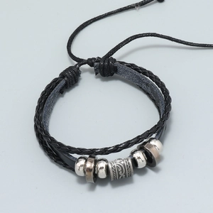 Detail of multi-layer braided leather bracelet featuring vintage engraved metal cylinder beads