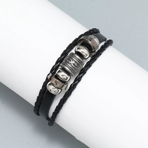 Macro detail of multilayer black leather braid bracelet with vintage carved metal beads
