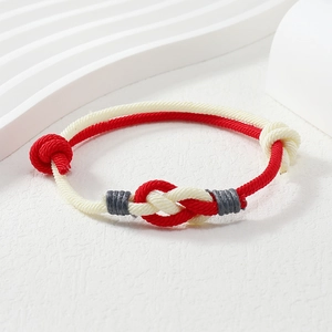 Close-up of handmade red and white braided couple bracelet with intricate knots