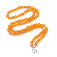 Detail view of long beaded necklace featuring amber-colored beads and a silver lotus pendant