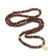 Detail of beaded long necklace with tiger eye stones and golden Zen symbol pendant