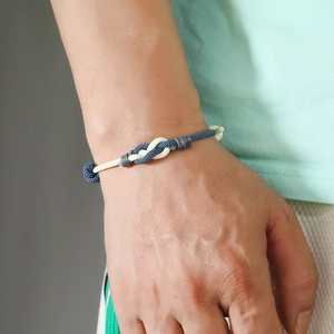 Close-up of hand-woven blue and white couple bracelet with interlocking rope knot detail