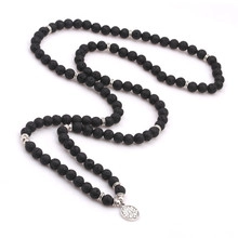 Detail of beaded tree of life necklace with matte black beads and silver pendant