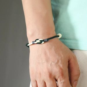 Close-up of hand-woven tricolor couple bracelet in green, beige and grey cord