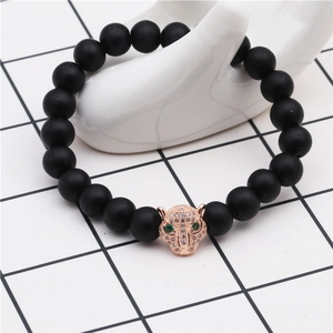 Detail of rose gold leopard charm with green eyes on matte black beaded bracelet