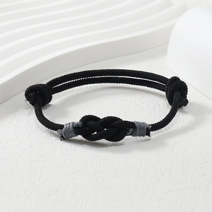 Detail of black woven rope bracelet with adjustable nautical knots on white props