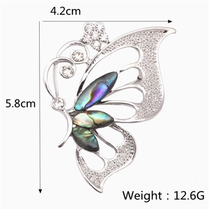 Détail macro d'une broche papillon avec incrustations de nacre et cristaux blancs