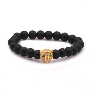 Detailed close-up of a matte black bead bracelet featuring a gold leopard head with green eyes
