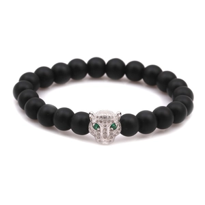Close-up of leopard head charm with green eyes on matte black beaded bracelet