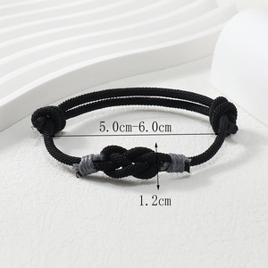 Macro detail of hand-woven black cord bracelet with adjustable knots and size labels