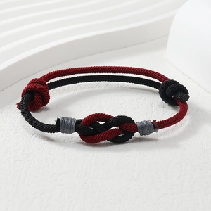 Close-up of handmade red and black braided rope bracelet with intricate knot detail