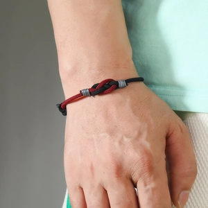 Detailed close-up of handmade red and black woven couple bracelet with knot detail