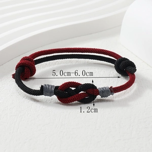 Macro detail of hand-woven red and black cord bracelet with sliding knot and size markings