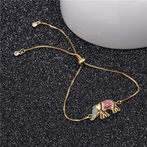 Macro detail of adjustable gold bracelet with micro-pave colored gemstone elephant pendant