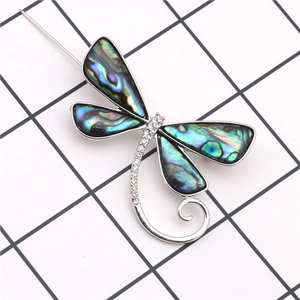 Détail d'une broche libellule argentée avec des ailes en nacre d'abalone et cristaux brillants