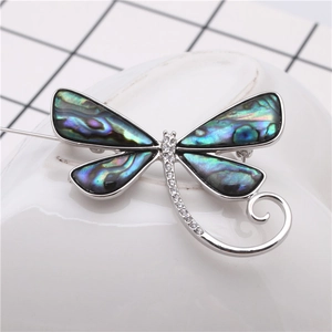 Vue macro d'une broche libellule avec ailes en nacre d'abalone et détails en cristal