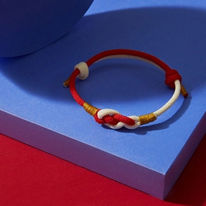 Handmade red and white woven couple bracelet with a decorative knot and gold silk accents