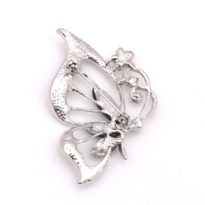 Détail de la broche papillon argentée montrant le fermoir de sécurité et la texture métal
