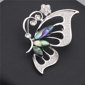 Détail macro d'une broche papillon avec ailes en nacre d'abalone et placage en argent