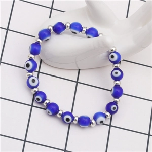 Retro blue evil eye beaded bracelet with silver spacers on white ceramic hand display