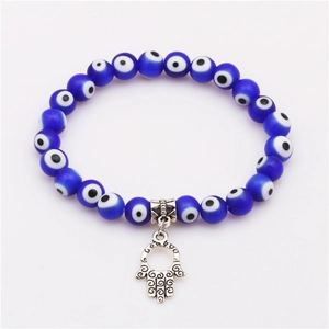 Macro detail of Hamsa Hand charm and blue Evil Eye resin beads on an elastic bracelet