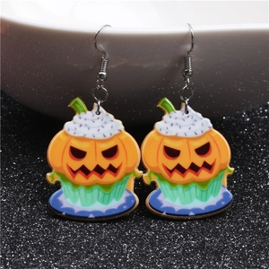 Detail view of Halloween pumpkin cupcake earrings with white frosting on acrylic