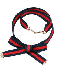 Detailed view of striped web ribbon belt with golden horsebit buckle and bow detail
