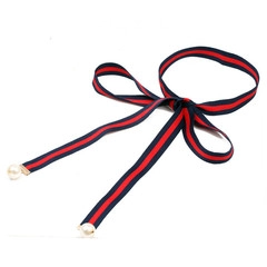 Detail of red and blue striped ribbon tie with gold metal clasps and white faux pearls