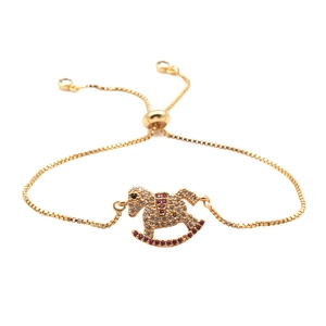 Detalle de pulsera de cadena de caja dorada con colgante de caballo balancín de circonita