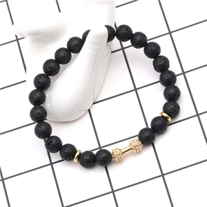 Detailed macro shot of 8mm volcanic stone beads with a golden dumbbell zircon charm