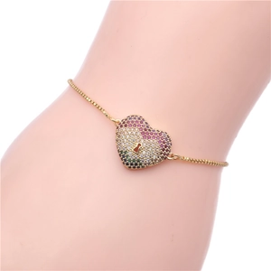 Macro shot of gold box chain bracelet with a colorful heart lock pendant set in pavé zircons